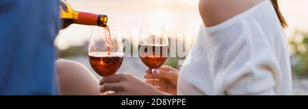 Panoramic shot of man pouring wine in glasses near girlfriend on beach Stock Photo