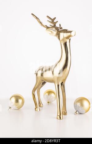 Vertical shot of a golden deer statue with Christmas ornament balls isolated on a white background Stock Photo