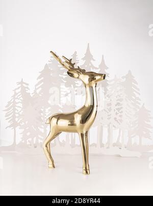 Vertical shot of a golden deer souvenir with pine trees for Christmas in the background Stock Photo