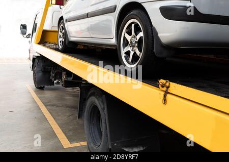 Broken car on flatbed tow truck being transported for repair Stock Photo