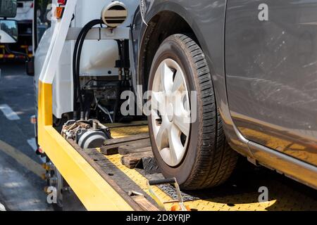 Broken car on flatbed tow truck being transported for repair Stock Photo