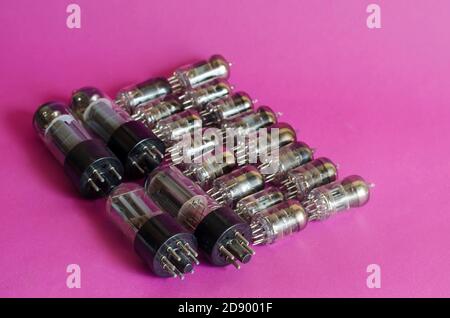 Group of random radio tubes on a pink background. Vacuum tubes of various sizes and powers. Obsolete radio parts. Collecting. Selective focus. Stock Photo