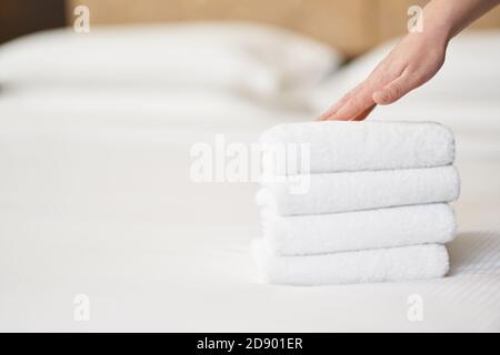 Close up of stack of clean towels on a blanket in bed after cleaning in hotel room. Copy space. Hotel service concept Stock Photo