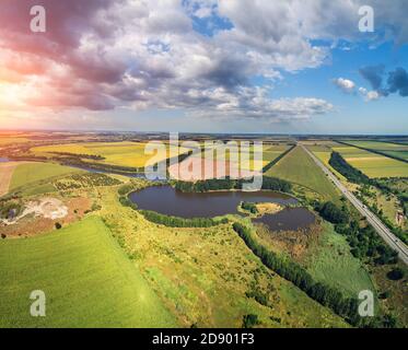 Rural landscape with beautiful sky, aerial view. View of colorful arable fields, lake and highway in summer Stock Photo