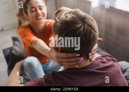 back view of man near happy woman embracing his neck on blurred background Stock Photo