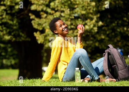 Portrait of healthy young woman with apple in park Stock Photo