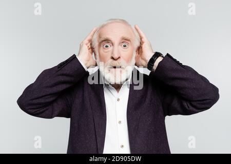 Surprised elderly man in jacket and shirt touching head isolated on grey Stock Photo