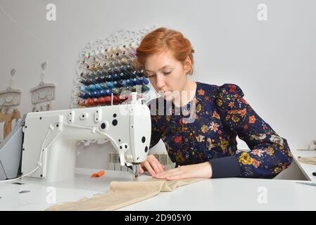 Young woman working on a sewing machine in a sewing studio Stock Photo