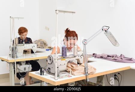 Two caucasian women seamstress at work on sewing machines in a sewing studio Stock Photo