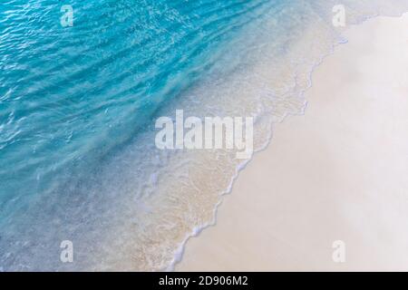 Soft wave of blue ocean on sandy beach. Relaxing ocean coast background. Soft gentle waves splashing on white sand, tropical beach shore coastline Stock Photo
