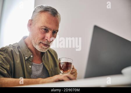 Concentrated aged man looking at a laptop screen with concern Stock Photo