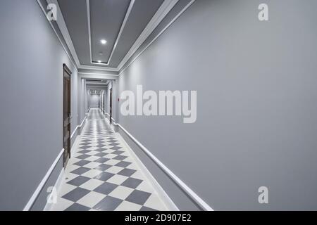 Empty long gray corridor in hotel with closed doors Stock Photo