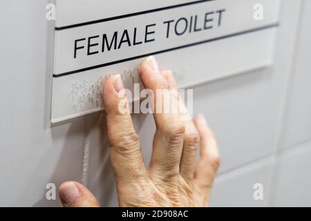Finger reading braille tactile on toilet signage Stock Photo