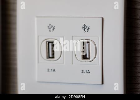 USB plug for charging power of all devices at the wooden wall. USB slot is attached to the wall for charging. Stock Photo