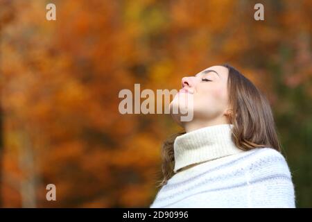 Relaxed woman breathing fresh air in autumn in a beautiful park or forest Stock Photo
