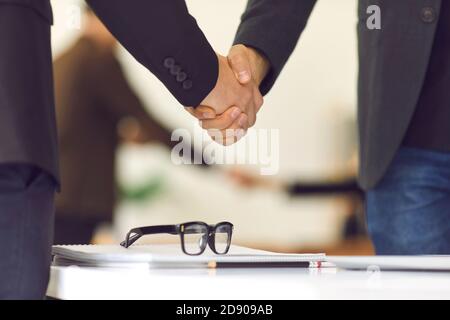 Close up of two businessmen shaking hands over a negotiating table in the office. Stock Photo