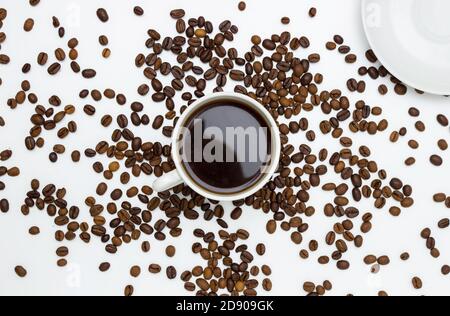 White Cup and saucer with coffee and coffee beans. Top view, white background. Free space for text. Stock Photo