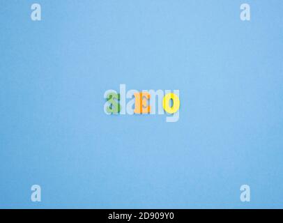 The word SEO on a blue background of wooden multicolored letters. Stock Photo