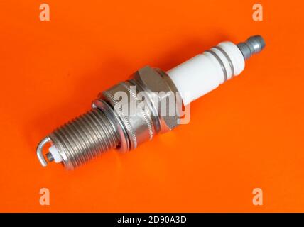 The Car spark plug on orange background. Electric device for machine,Space for design Stock Photo
