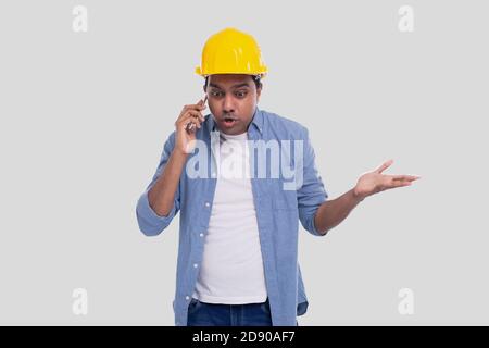 Construction Worker Talking on the Phone Angry. Architect Holding Phone. Yellow Hard Helmet. Man Isolated Talking on Phone Confused. Man Having a Call Stock Photo