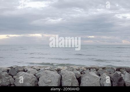 Rainy sky with a lot of grey clouds on a rocky beach, in the north of Italy in the Fall Stock Photo