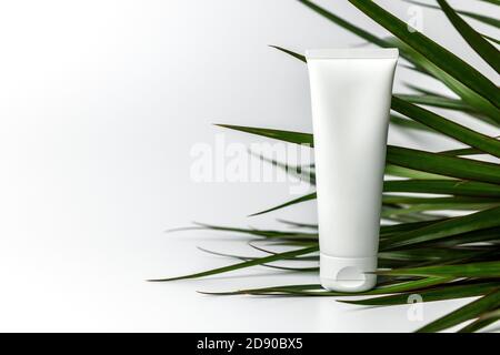 body skin cream tube and palm leaves on white background with copy space Stock Photo