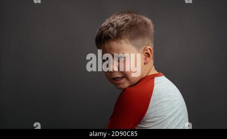 Little boy is upset, sad, focused and serious. The child is offended. isolated on grey background with copy space at left Stock Photo