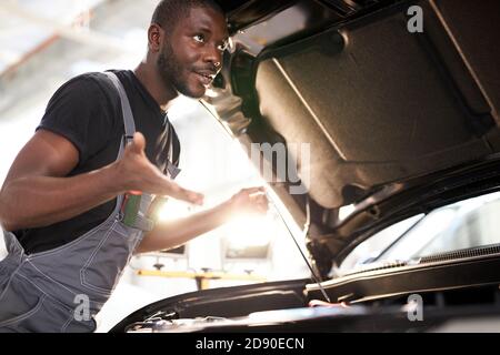 black african auto mechanic does not understand how to troubleshoot the machine, he has no tools for repair. misunderstanding Stock Photo