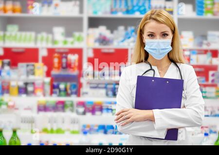 portrait of beautiful young woman pharmacist in uniform at modern drugstore, attractive diligent druggist at work, ready to help customers Stock Photo