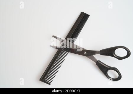 stainless steel scissors with black handle lie and comb on a light table Stock Photo