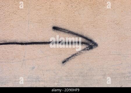 Black arrow painted on a beige wall. Stock Photo