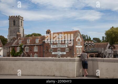 A man stood on a bridge watching the river in Wareham, Dorset i the UK, taken on the 23rd July 2020 Stock Photo