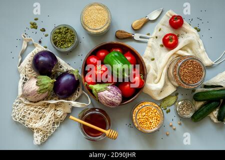 Zero waste healthy food-cereals, seeds, vegetables flat lay on grey background. Groceries in textile bags,glass jars, wooden bowl. Eco friendly plasti Stock Photo
