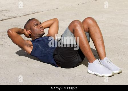Portrait of healthy young black man doing sit ups outdoors Stock Photo