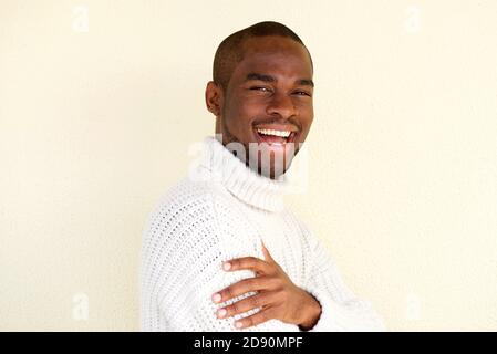 Close up side portrait of attractive african american man in sweater smiling against light background Stock Photo