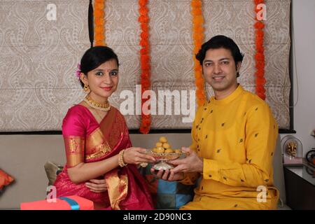 Indian couple with sweets and gifts while celebrating Diwali, Deepavali or Dipavali festival. Stock Photo