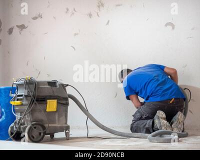 worker smoothes the wall with machinery with mask Stock Photo