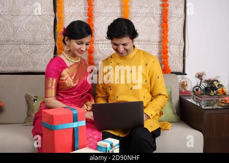 Indian young family couple choosing new home online, search real estate to buy or rent, house for sale on screen of computer. Stock Photo