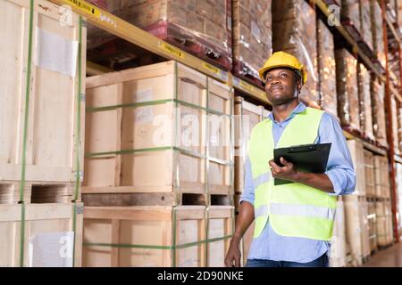 Portrait of african black warehouse worker hold clipboard and looking forward in large warehouse distribution center environment. Using in business wa Stock Photo