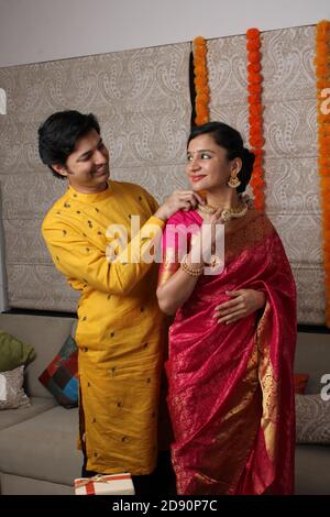Indian man tying or presenting gold necklace to his beautiful wife on birthday, valentine's day, anniversary or Diwali festival. Stock Photo
