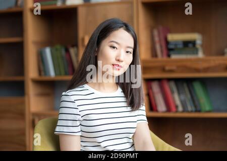 Portrait of beautiful young Asian woman in striped t shirt sitting in chair Stock Photo
