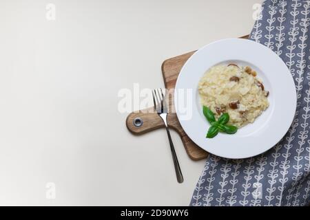 Vegetarian gourmet mushroom risotto on a white plate, yellow background, view from above. Risotto is a northern Italian rice dish cooked with broth until it reaches a creamy consistency. Stock Photo