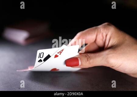 Close up of a woman hand holding playing cards in a dark table. Online gambling. Addiction. Falling playing cards and poker chips Stock Photo