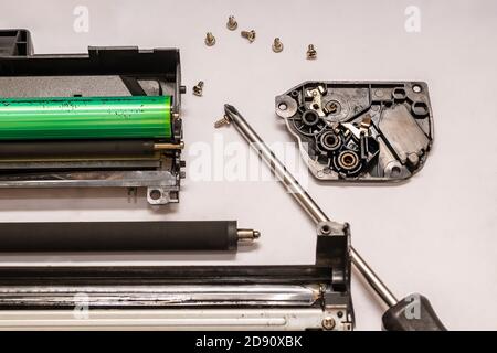 a set of components of the disassembled laser toner cartridge, screwdriver and bolts, lies on a light white surface Stock Photo