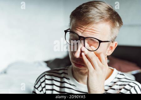 Young businessman feeling sore and tired. Frustrated millennial covering his face with hands . Upset Worker in eyeglasses overworking exhausted. troub Stock Photo