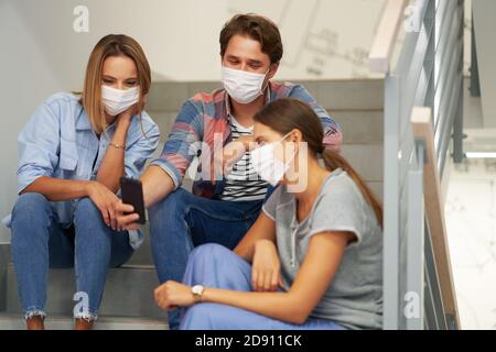 Couple of students wearing masks relaxing in the campus Stock Photo
