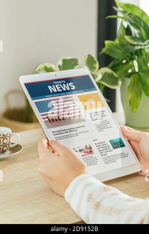 Stock photo of a woman reading news in a website on her tablet in the living room. Concept of online information and reading newspapers on the interne Stock Photo