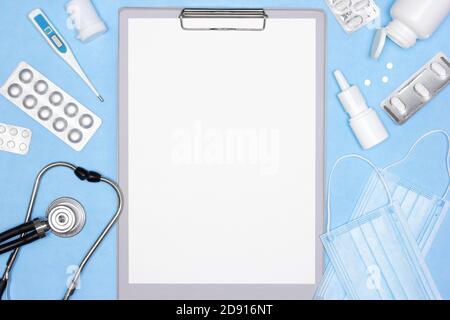 Clipboard with blank white paper, stethoscope, thermometer, medicines on blue background. Medical concept Stock Photo