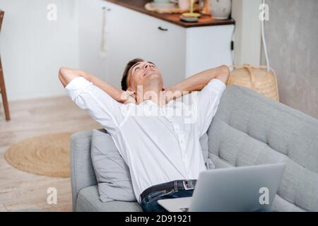young man with a laptop is relaxing in the living room . Stock Photo