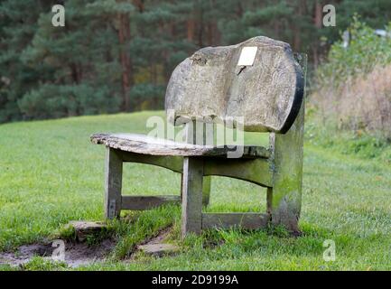 Rough cut wooden memorial park bench with dedication plate isolated outdoors in UK country park. Stock Photo
